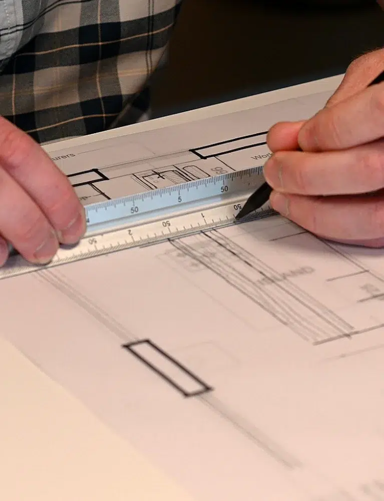 Hobson's Choice designer plotting a design over architect plans using a scale ruler.