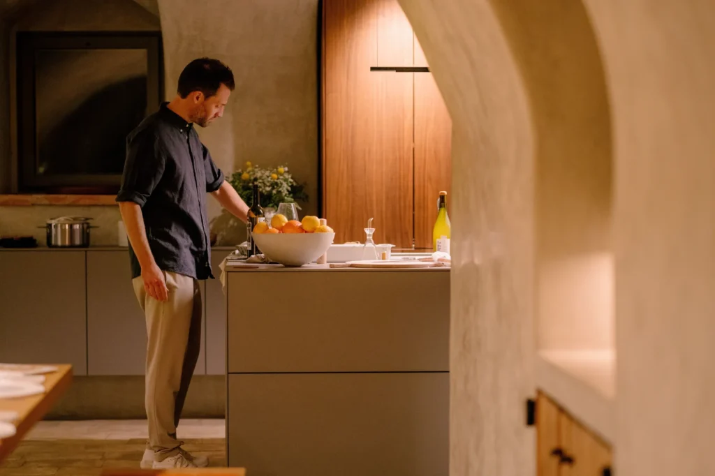 A man cooking on the end of a bulthaup kitchen island in a Mediterranean-style property