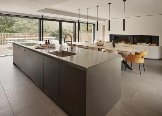 Stainless steel kitchen island with anthracite cabinetry and open-plan dining area
