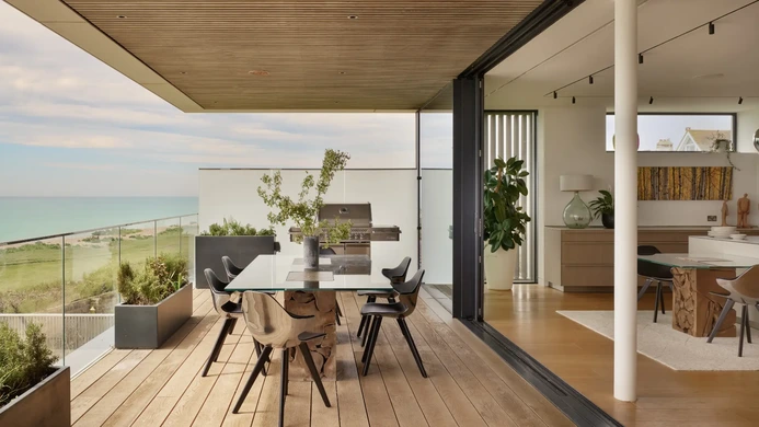 Open-plan kitchen with panoramic glazing and indoor-outdoor dining connection