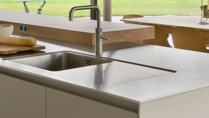 Stainless steel kitchen sink and drainer formed from a single worktop surface