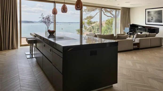 Dark handleless kitchen island with integrated hob and bar seating