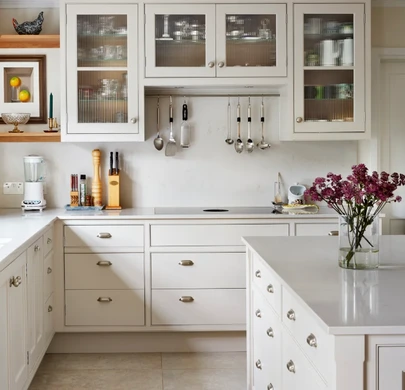 White painted kitchen cabinetry with glazed doors and traditional handles