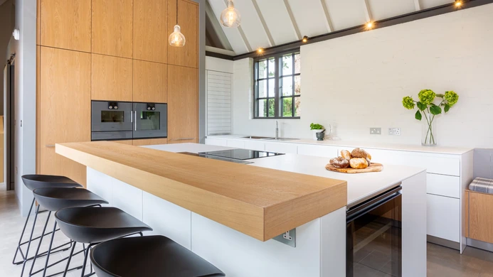 Timber breakfast bar with black stools in a light contemporary kitchen
