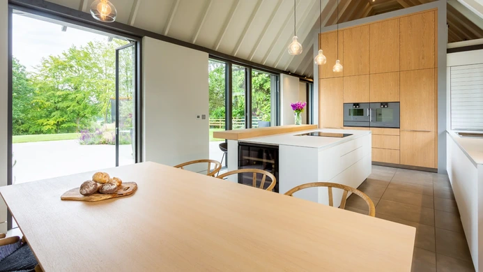 Spacious open-plan kitchen combining white cabinetry and natural timber