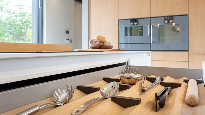 Warm timber kitchen cabinetry with integrated ovens and storage