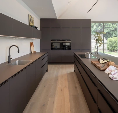 Contemporary dark brown kitchen with tall cabinetry and warm timber flooring