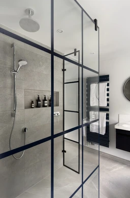 Walk-in shower behind a full-height deep-blue Crittall-style glass screen