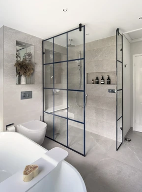 Freestanding bath beside the full-height deep-blue framed walk-in shower
