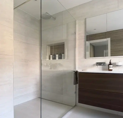 Walk-in shower with frameless glass screen and neutral stone-effect tiles