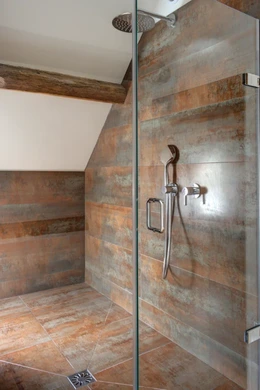 Walk-in shower with copper-effect wall tiles and glass enclosure