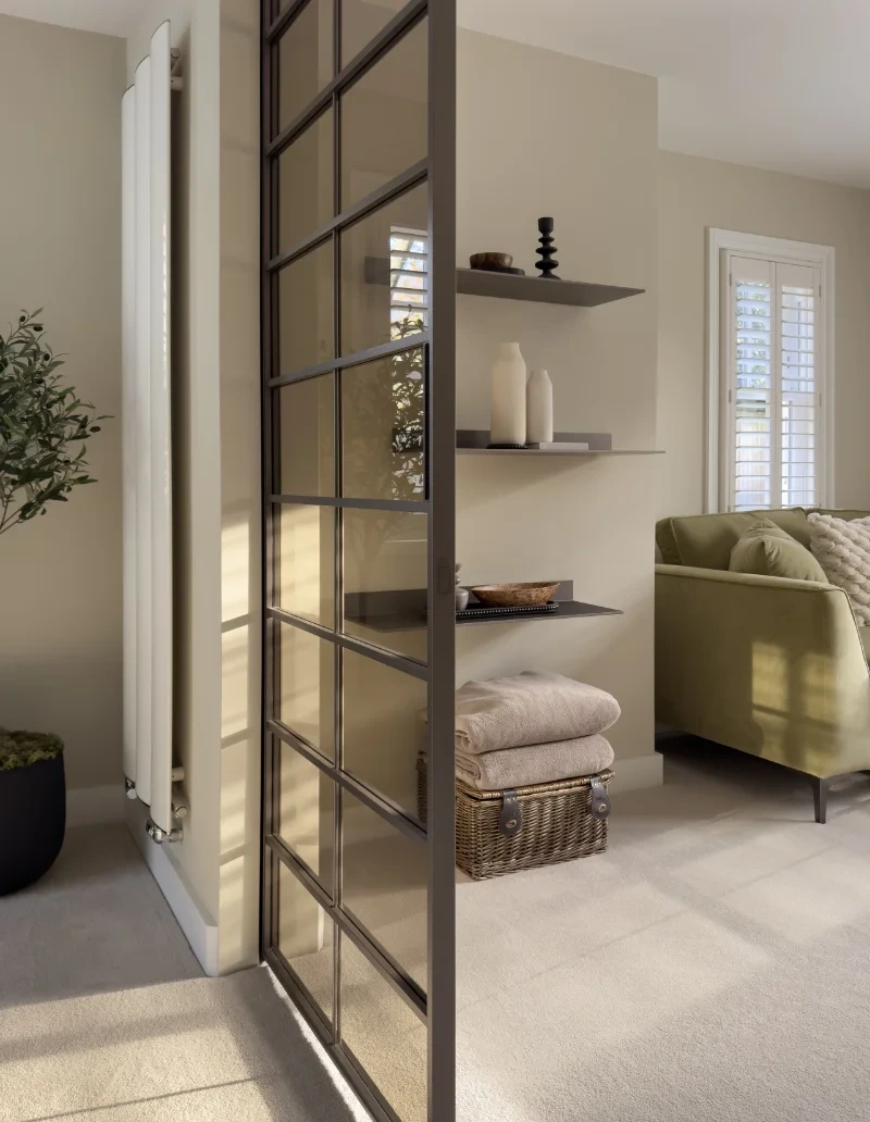 Black-framed Rimadesio glass sliding doors with horizontal divisions separating a light sitting room from an adjoining space