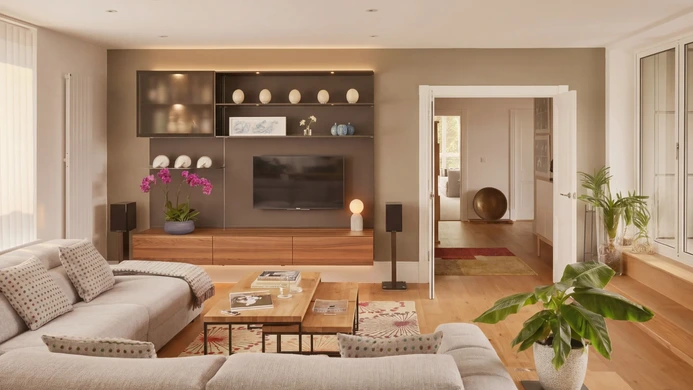 Bespoke living-room TV wall with walnut base cabinets and illuminated display shelves