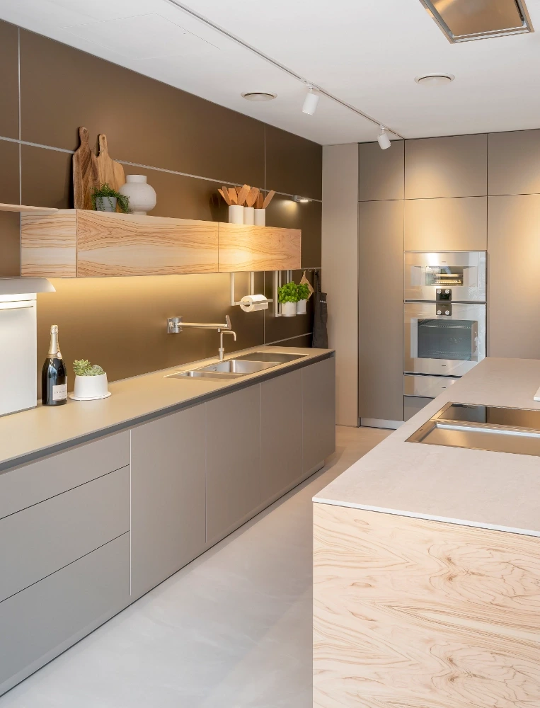 Tall bank of dark bulthaup b3 kitchen cabinetry with integrated Gaggenau ovens beside a light-coloured island