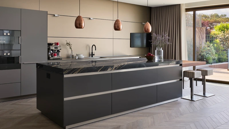 Dark stone bulthaup b3 kitchen with large island, marble worktop and garden view