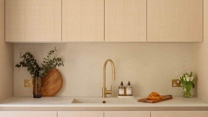 Pale quartz sink run with integrated sink, gold tap and white structured-oak wall cabinets