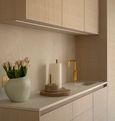Gold-finished undermount sink and matching pull-down tap set into the pale quartz worktop