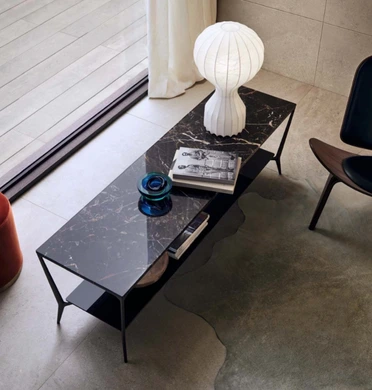 Black rectangular Rimadesio Planet coffee table beside a sofa, with books and decorative objects on its polished top