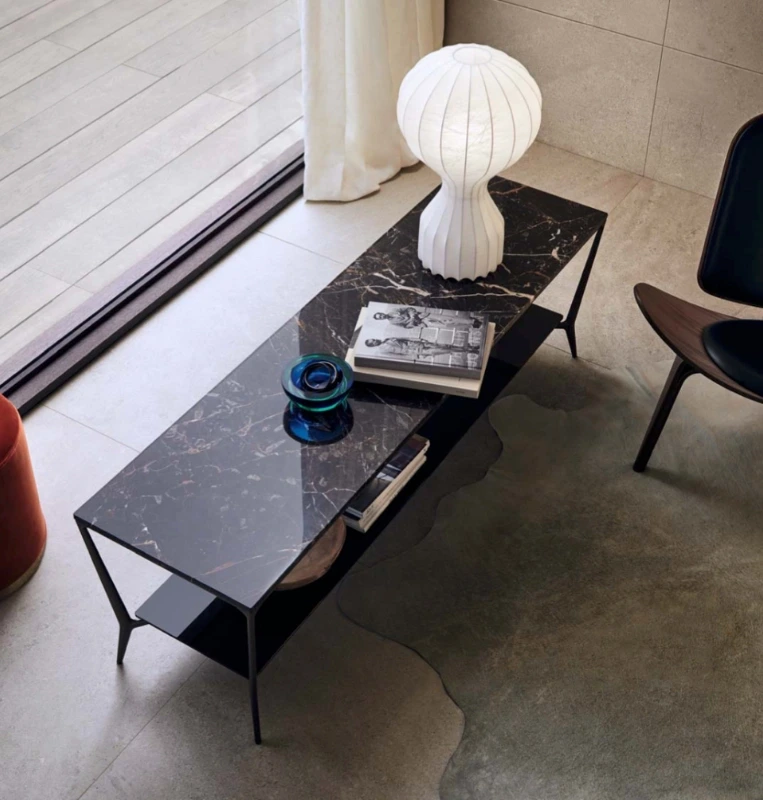 Black rectangular Rimadesio Planet coffee table beside a sofa, with books and decorative objects on its polished top