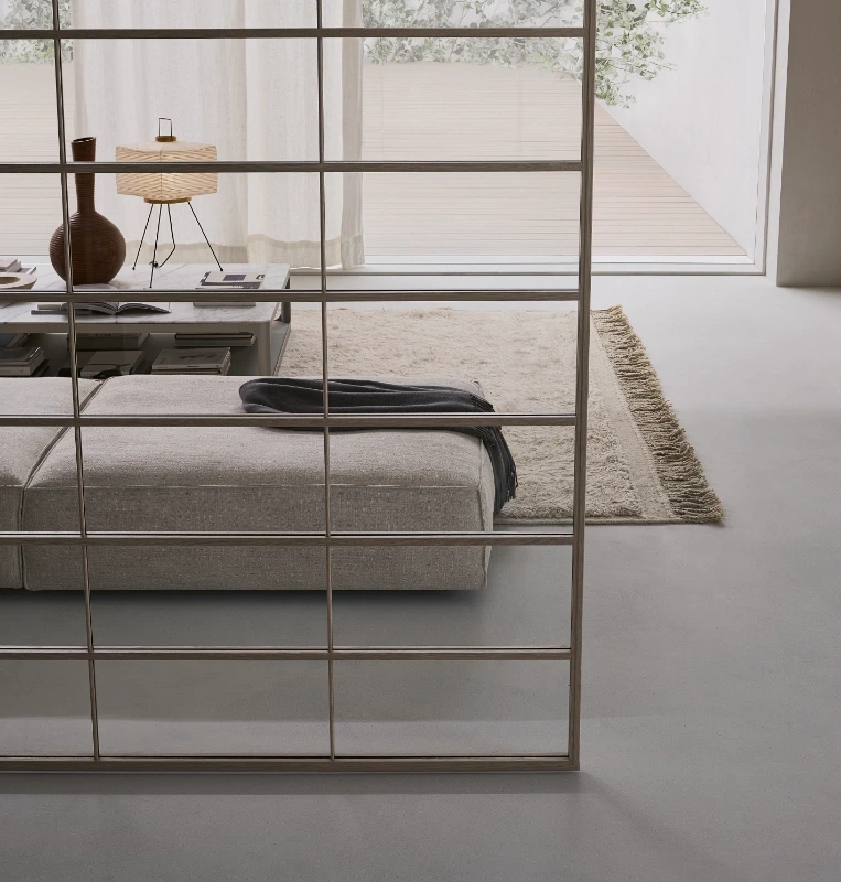 Rimadesio Soho sliding glass panel with aluminium grid in front of a low bed and neutral bedroom interior