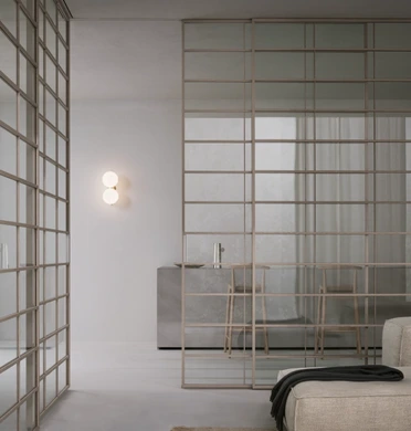 Rimadesio Soho sliding glass door dividing a bedroom from the adjoining space, with a fine aluminium grid across the glass panels
