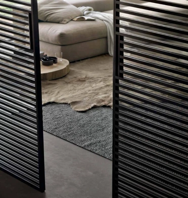 Close-up of black Rimadesio Stripe sliding door panels opening onto a furnished living area