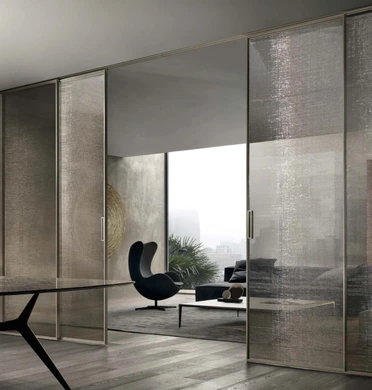 Floor-to-ceiling Rimadesio Velaria sliding glass panels partially open between contemporary living spaces.