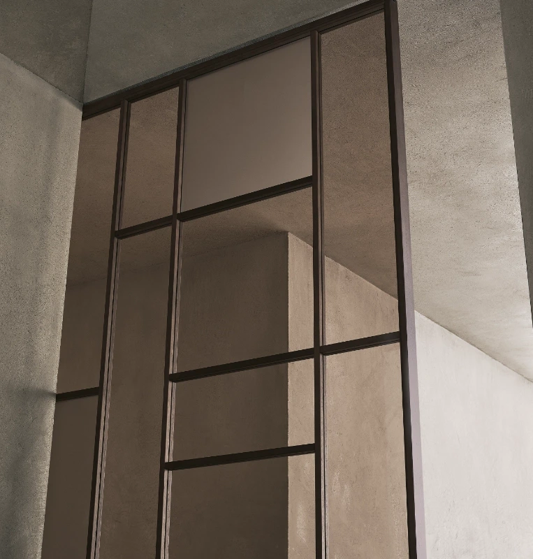 Close-up of the upper Rimadesio Maxi sliding door frame showing the irregular grid and glass panel divisions.