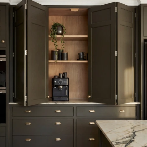 Open dark cabinet revealing a timber-lined coffee station with shelves and small-appliance storage.