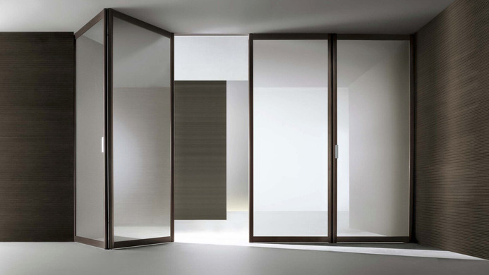 Rimadesio Siparium folding glass doors partly open within a dark timber and white interior.