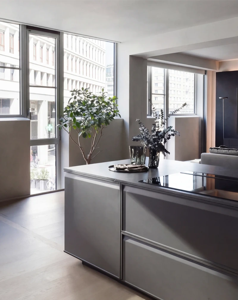 Compact Arrital apartment kitchen with a grey island beside floor-to-ceiling windows.