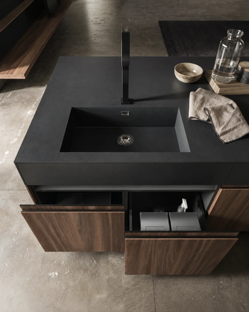 Dark Arrital island with an integrated sink and open storage beneath the worktop.