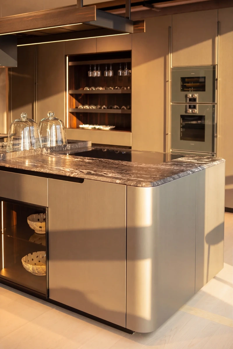 Curved corner of an Arrital island with a reflective metal finish and stone worktop.