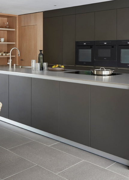 Contemporary bulthaup b3 kitchen with stainless steel island, dark tall cabinetry and timber wall storage