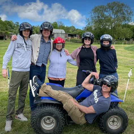 Members of the Hobson's Choice team pose with an off road quad bike at a team building outdoor event.